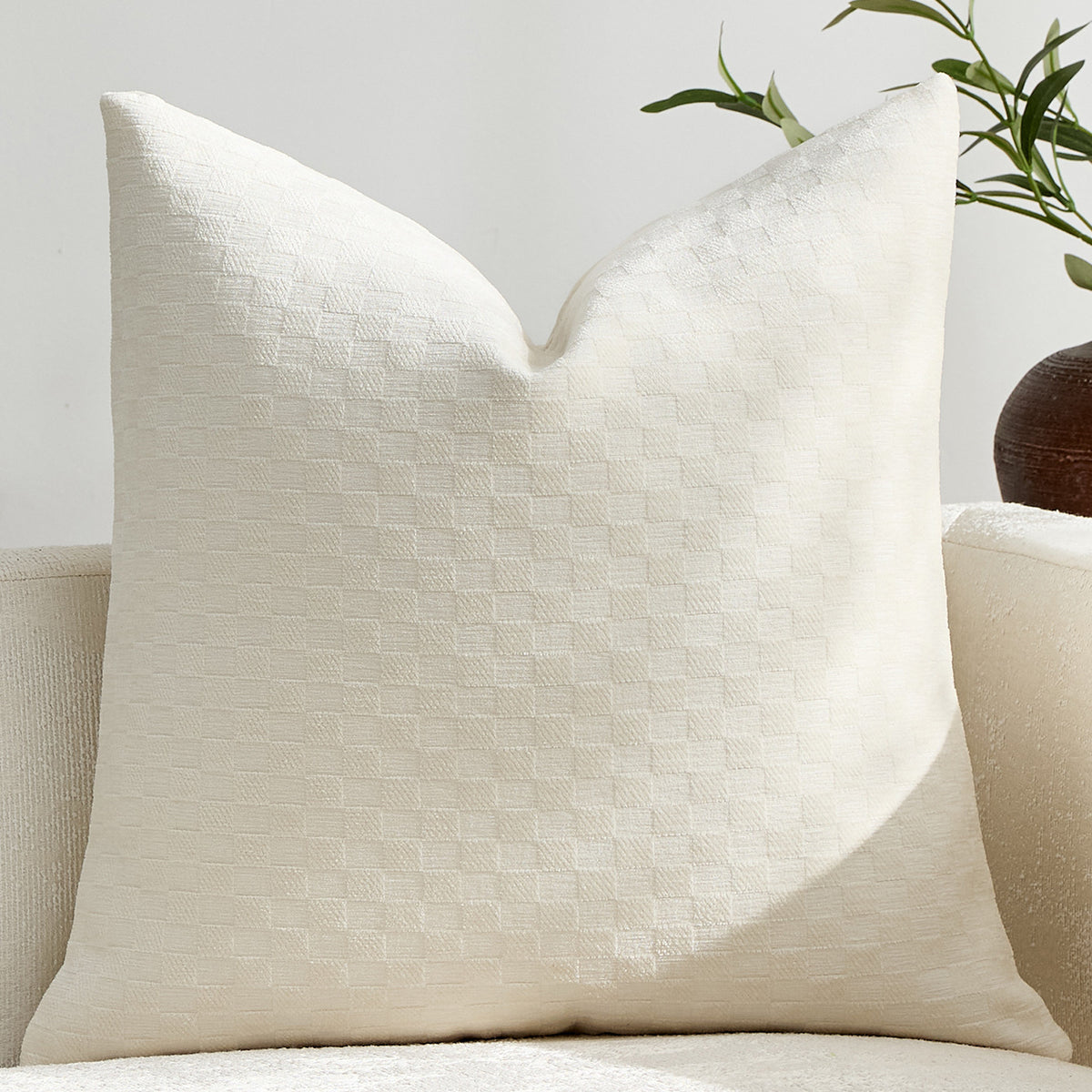 Raised checkerboard chenille pillow cover in ivory on a white sofa in soft daylight