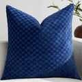 Raised checkerboard chenille pillow cover in blue on a white sofa in soft daylight