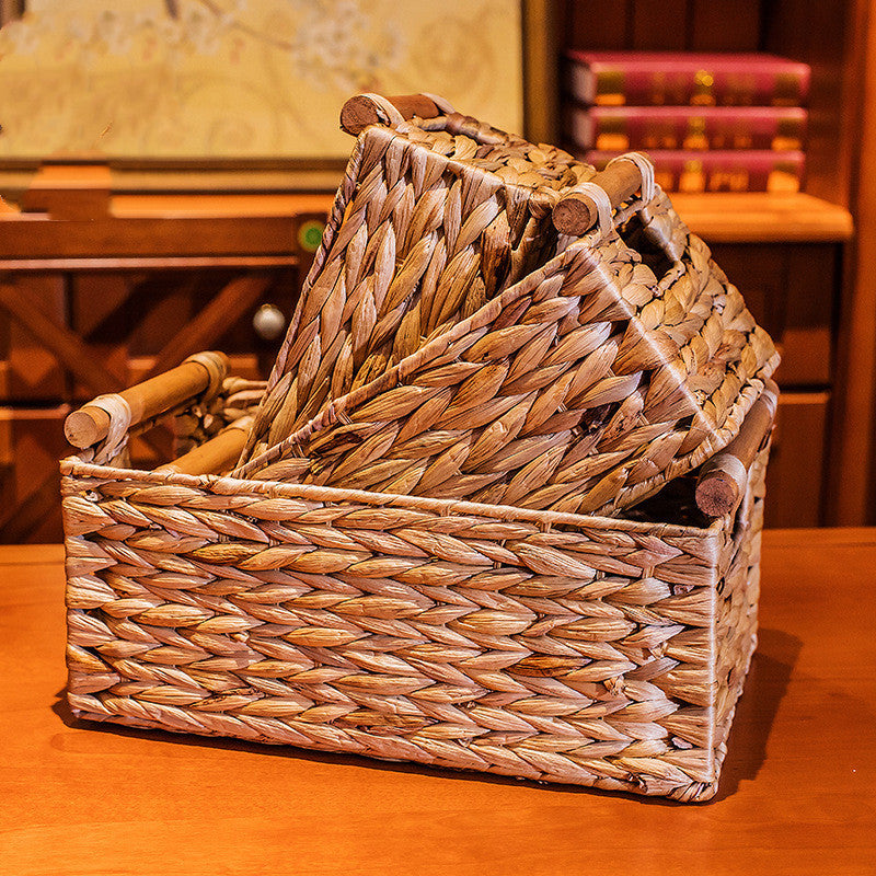 Three woven straw storage baskets nested on a wooden table, showing all three sizes