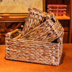 Three woven straw storage baskets nested on a wooden table, showing all three sizes