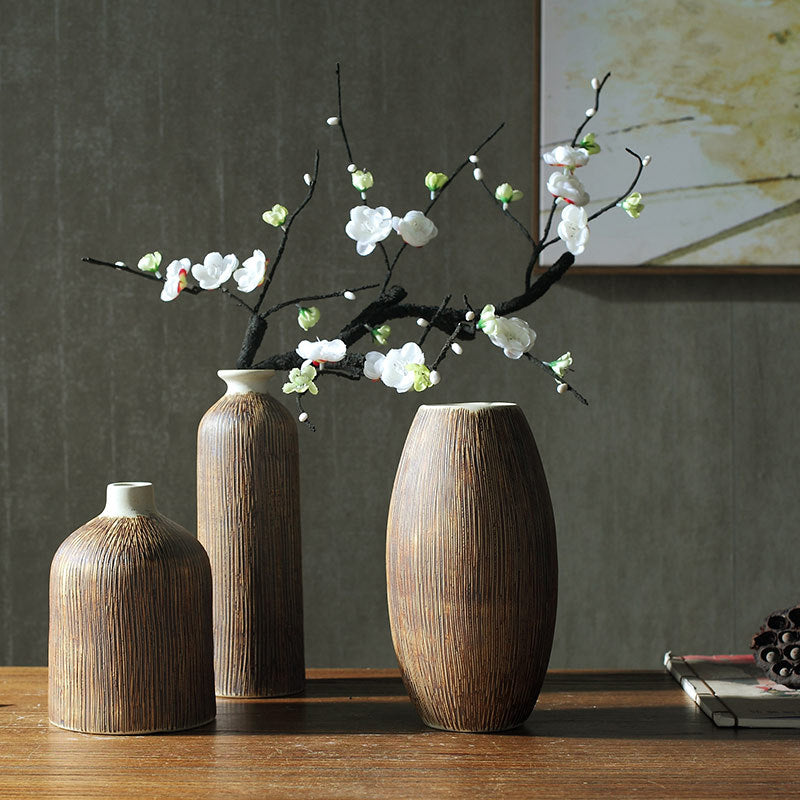 Set of 3 ribbed wood-grain ceramic vases on a wooden table, the tall bottle holding a white blossom branch