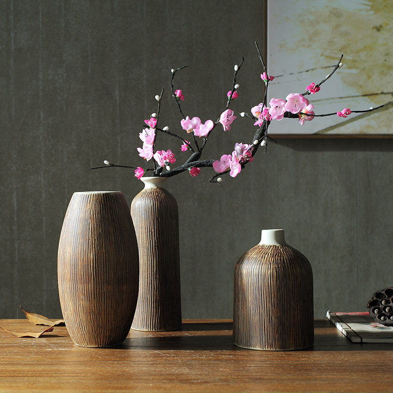 Set of 3 ribbed wood-grain ceramic vases with a pink blossom branch against a dark grey wall