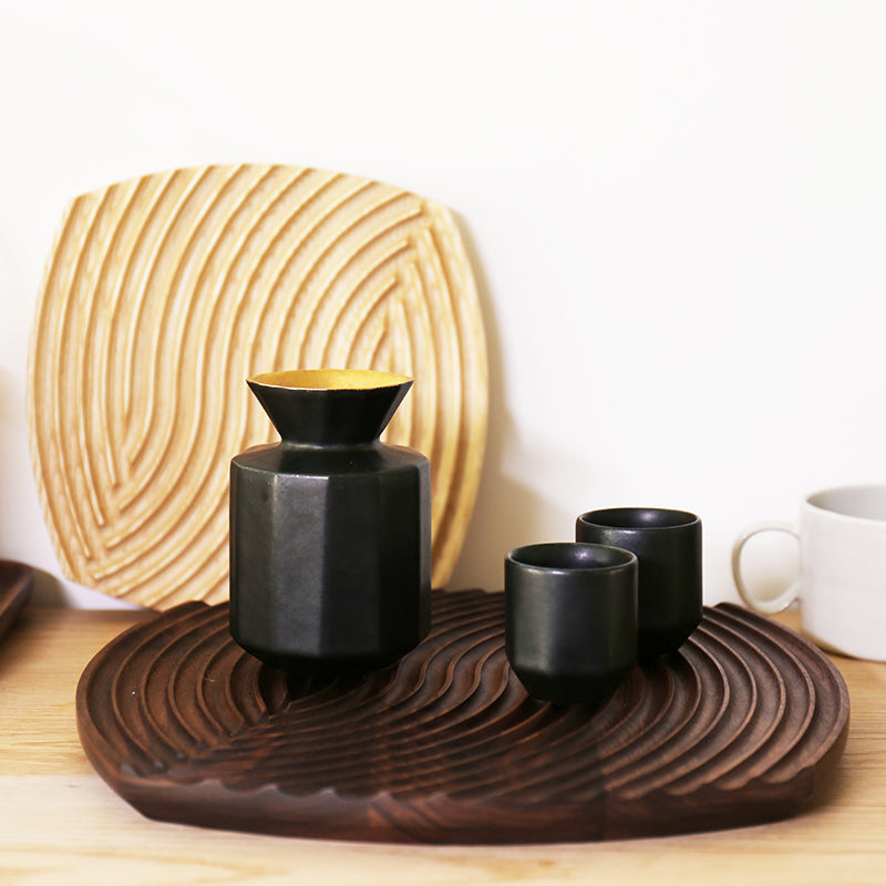 Walnut ripple-carved tray holding a black carafe and cups, a Natural ash tray propped behind