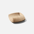 Ripple-carved wood trivet tray in Natural ash, medium 7.7 in size, on a plain light gray background