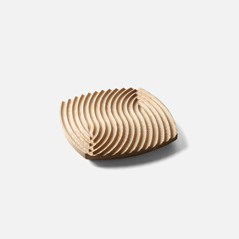 Ripple-carved wood trivet tray in Natural ash, medium 7.7 in size, on a plain light gray background