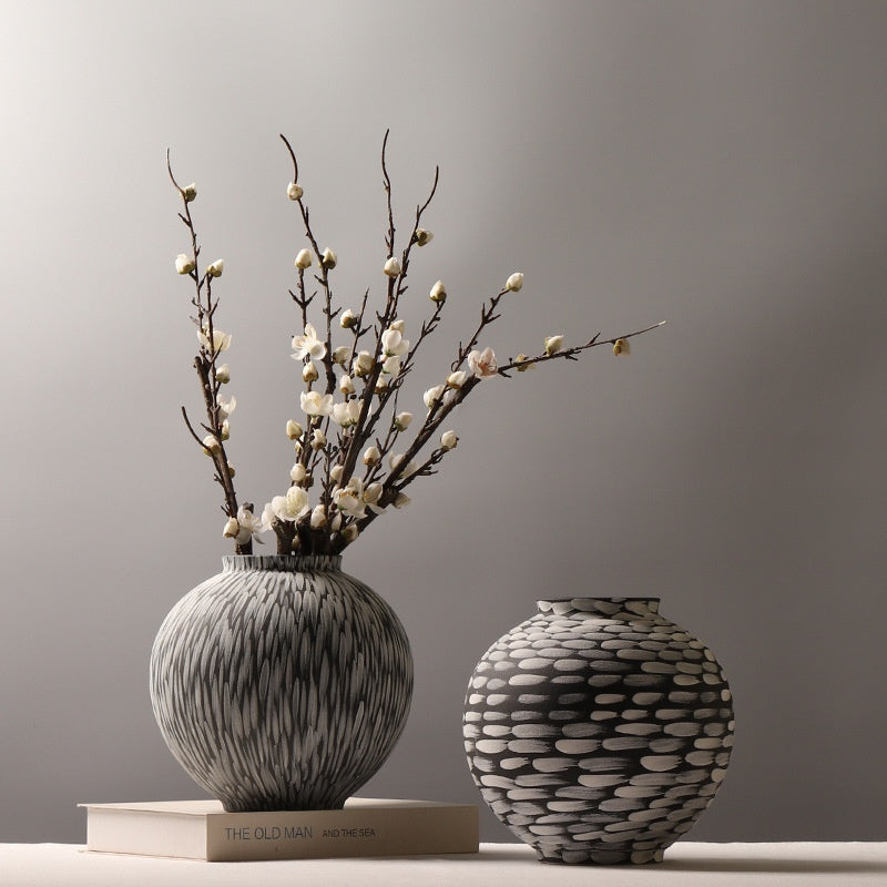 Vertical feather and horizontal dab round ceramic vases in charcoal and cream, one with a dried blossom branch