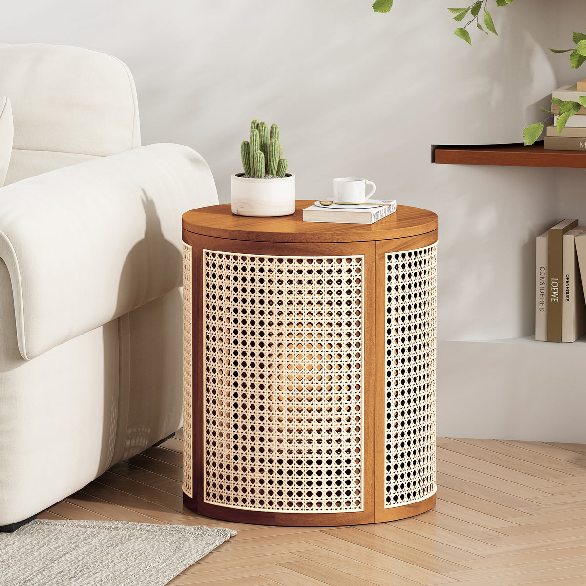 Round cane drum side table beside a cream sofa with a cactus, a book and a cup