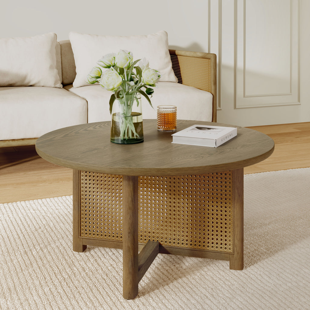 Round cane coffee table with white flowers and books in a paneled living room