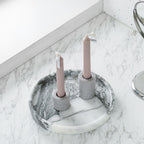 Round white marble tray holding two taper candles in gray holders on a marble counter