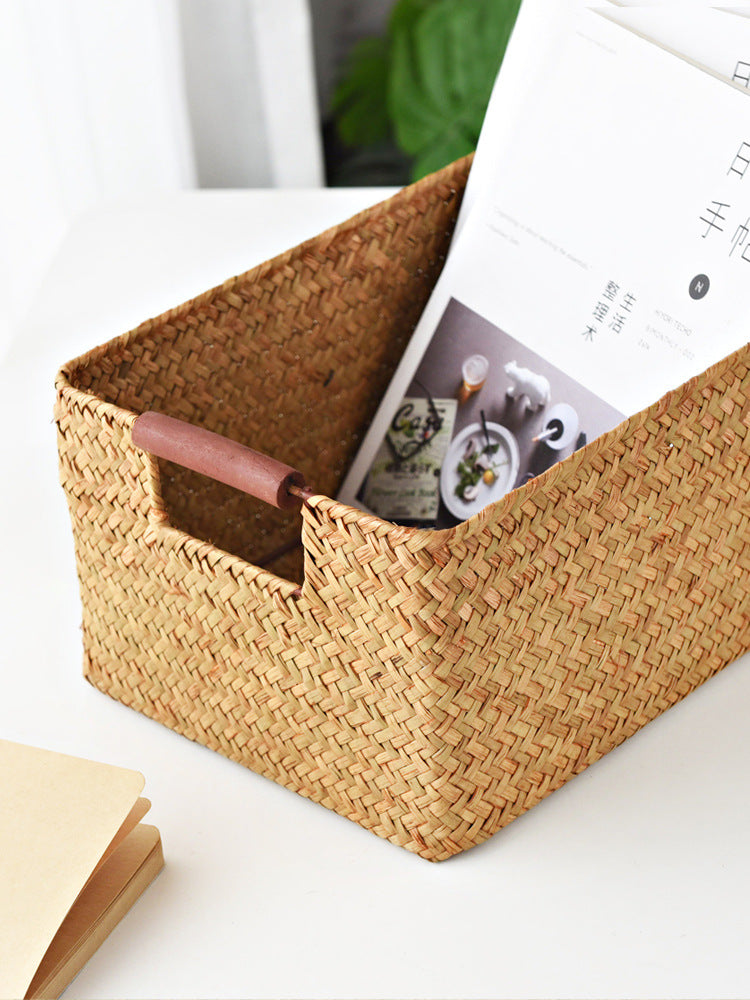 Seagrass storage basket with a magazine inside — detail of the wooden handle bar and herringbone weave