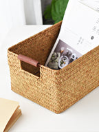 Seagrass storage basket with a magazine inside — detail of the wooden handle bar and herringbone weave
