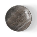 Silver gray travertine shallow bowl seen from above, showing banded stone, on a white background