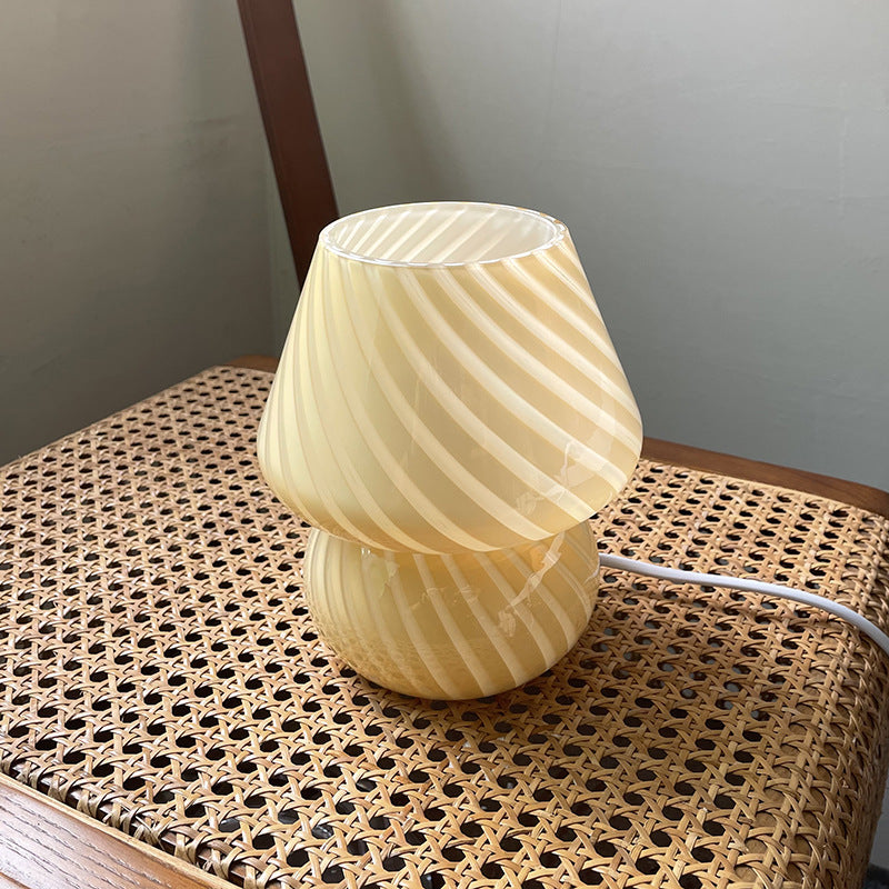 Beige swirl glass mushroom table lamp on a cane chair seat
