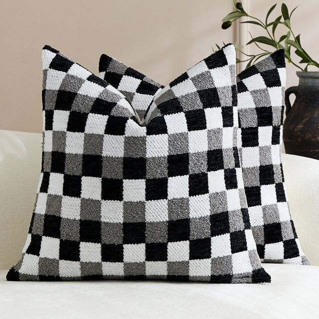 Black and white chenille checkerboard pillow covers, shown as a pair, on a cream sofa