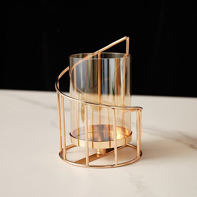 Short spiral gold-tone hurricane candle holder with amber-tinted glass on white marble