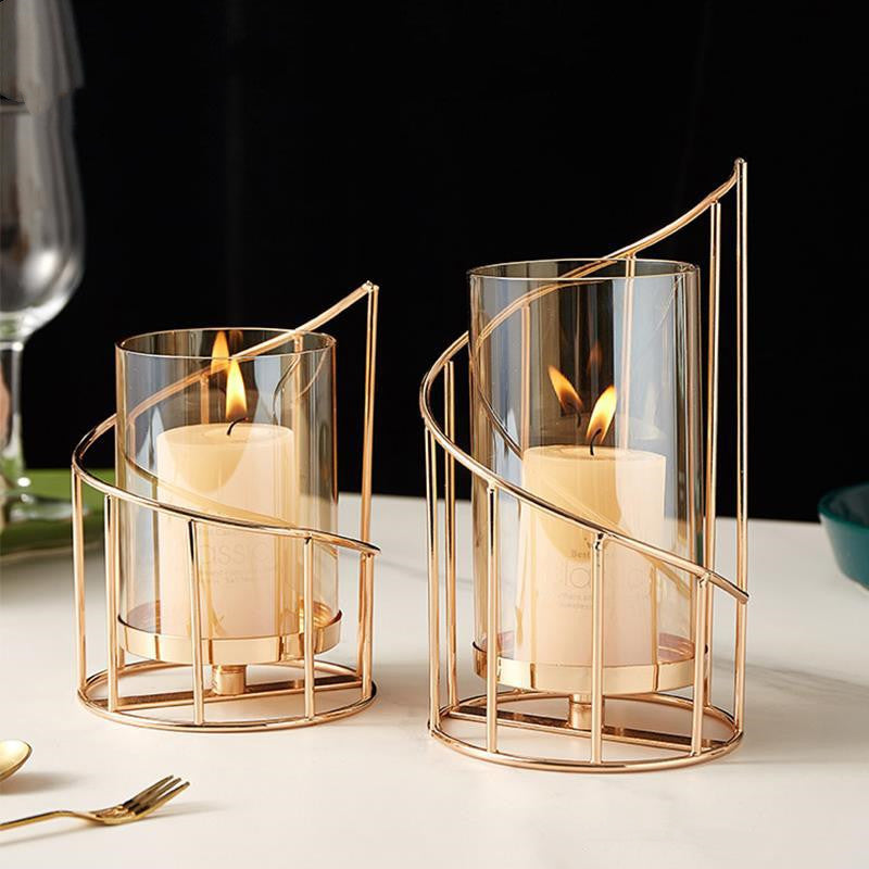 Short and tall spiral hurricane candle holders lit with pillar candles on a dining table