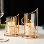 Short and tall spiral hurricane candle holders lit with pillar candles on a dining table