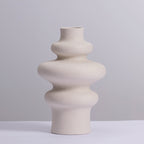 Three ring stacked ceramic vase in speckled matte cream against a soft grey backdrop