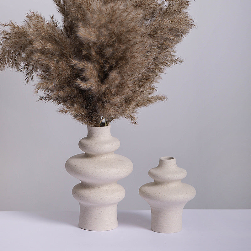 Three ring and two ring stacked ceramic vases in speckled cream, the taller holding dried pampas grass