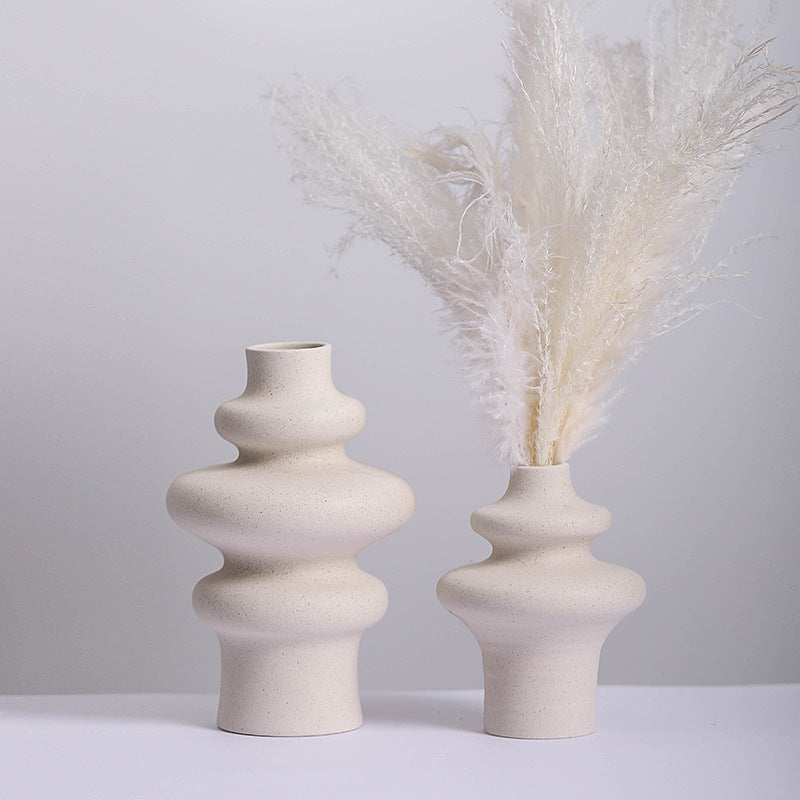 Three ring and two ring stacked ceramic vases in speckled cream, the shorter holding white dried pampas