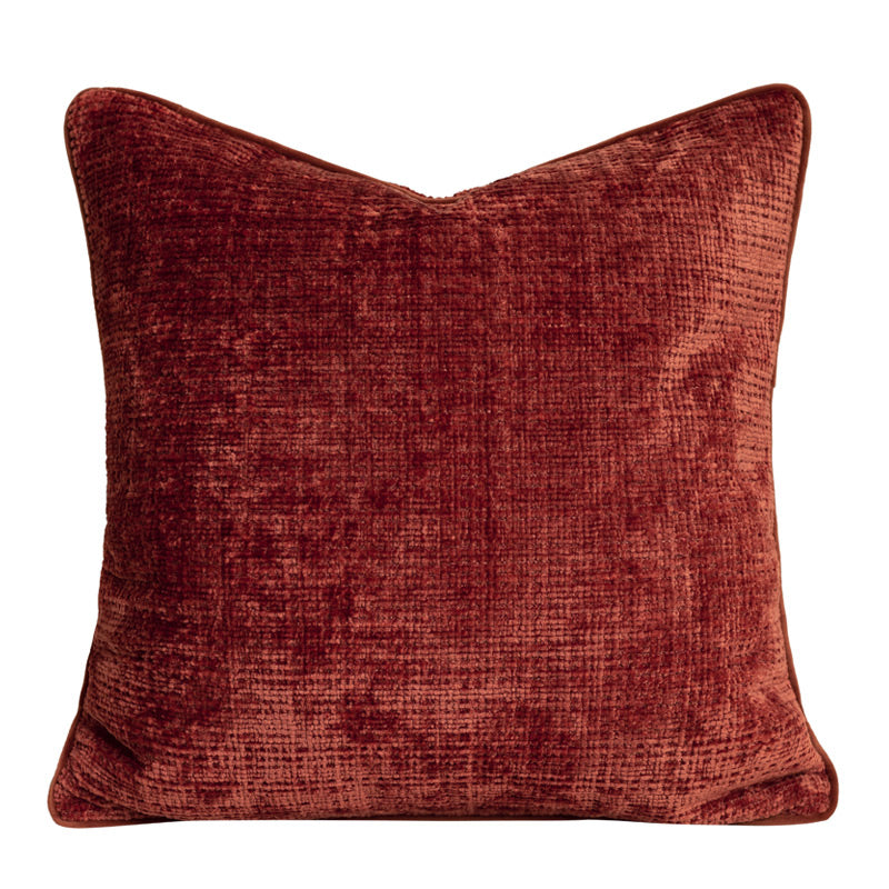 Textured chenille pillow cover in rust, square, with matching piping on a plain white background