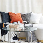 Textured chenille pillow covers in charcoal, rust, smoke and ivory on a cream sofa behind a glass table