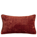 Textured chenille lumbar pillow cover in rust with matching piping on a plain white background