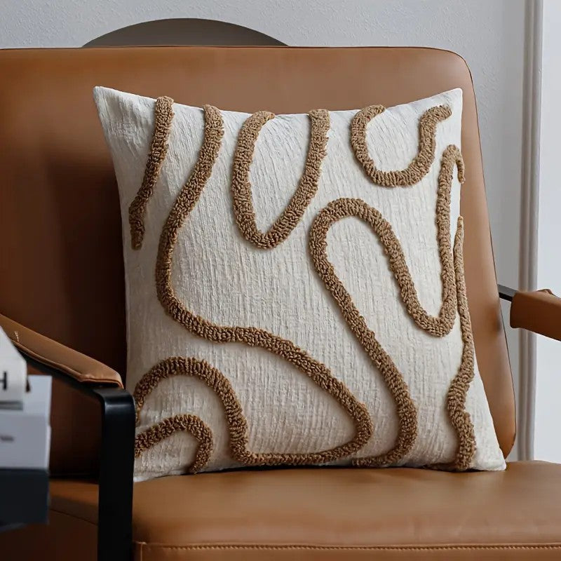 Tufted abstract line pillow cover with camel lines on cream, on a cognac leather lounge chair