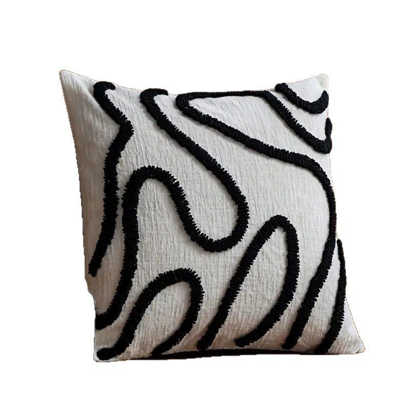 Tufted abstract line pillow cover with black lines on cream, angled on a plain white background