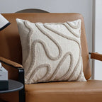 Tufted abstract line pillow cover with beige lines on cream, on a cognac leather lounge chair