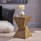 Hourglass side table with a vase and a glass on top beside a faux fur pillow
