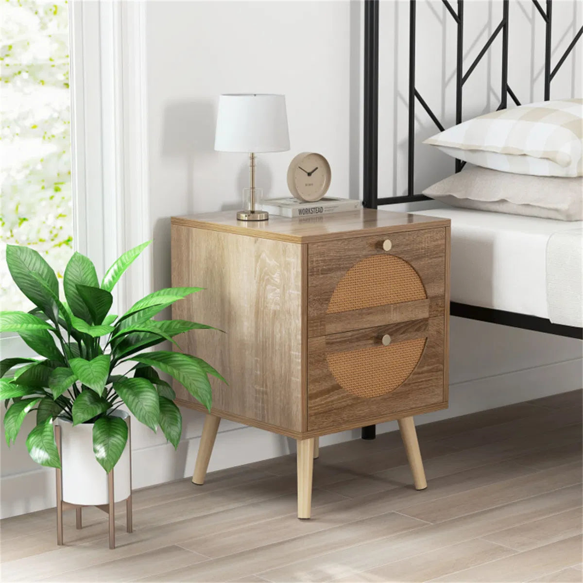 Two-drawer rattan nightstand beside a bed with a lamp, clock and potted plant