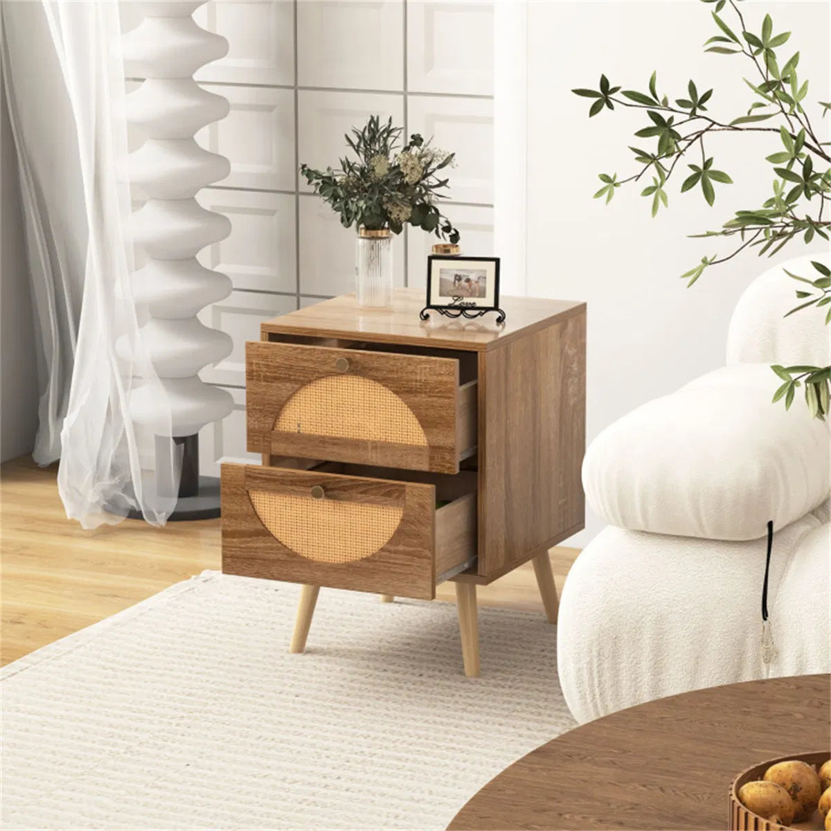 Rattan half-moon nightstand with both drawers open beside a cream armchair
