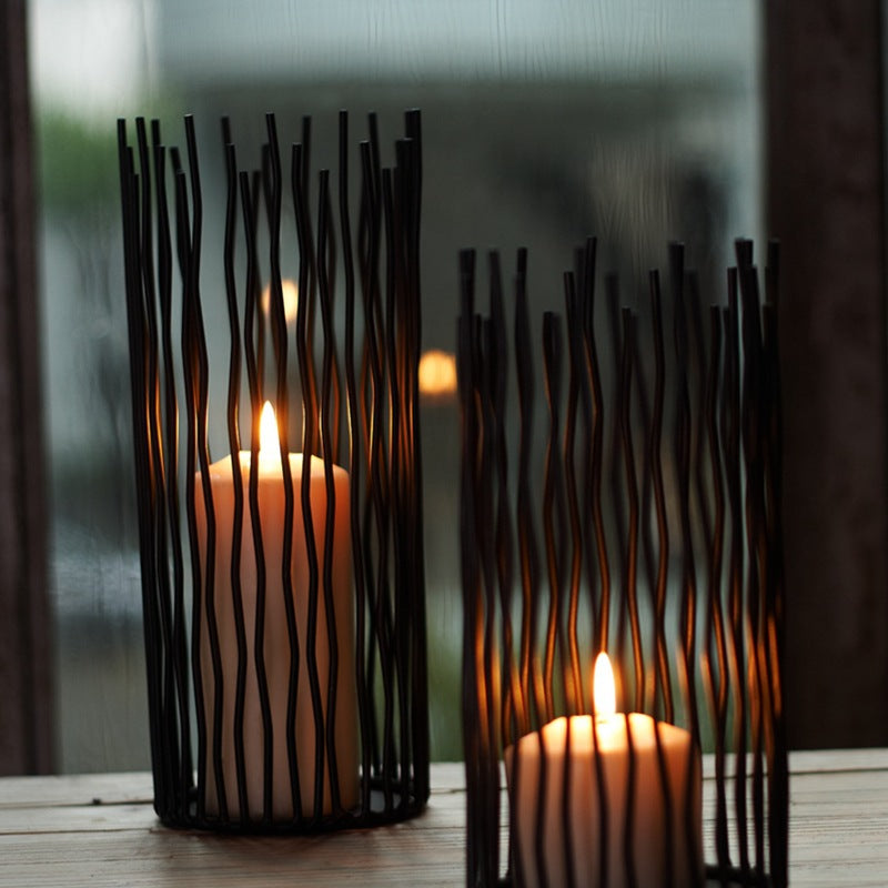 Black wavy iron rod candle holders around lit pillar candles — close view of the rods