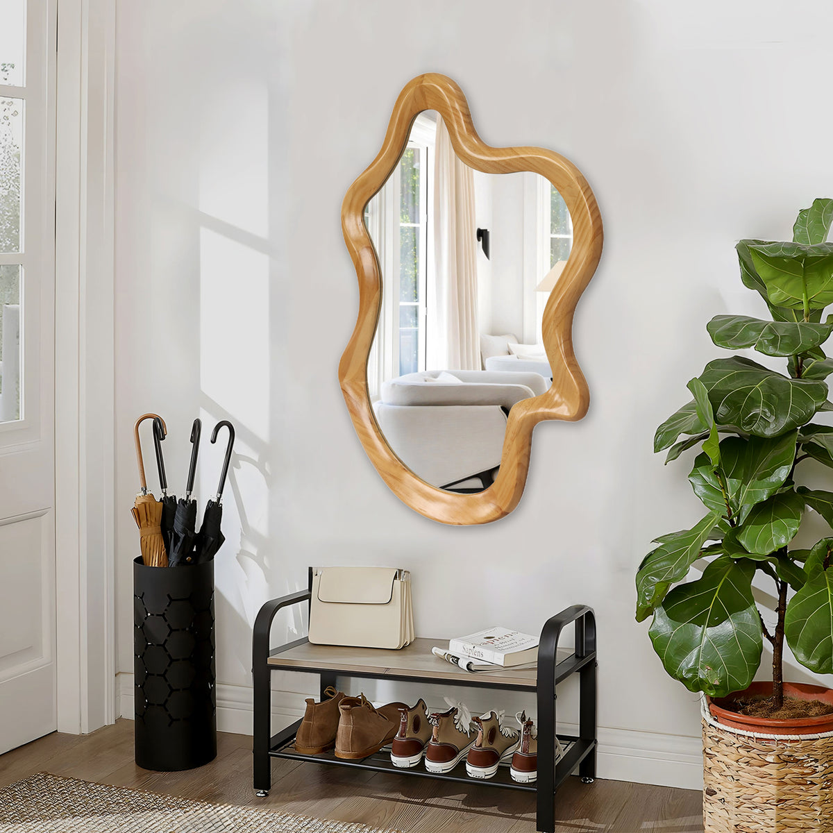 Wavy wall mirror with natural wood-finish frame in an entryway above a shoe bench