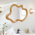 Wavy irregular mirror hung sideways above a white bathroom sink and brass sconce