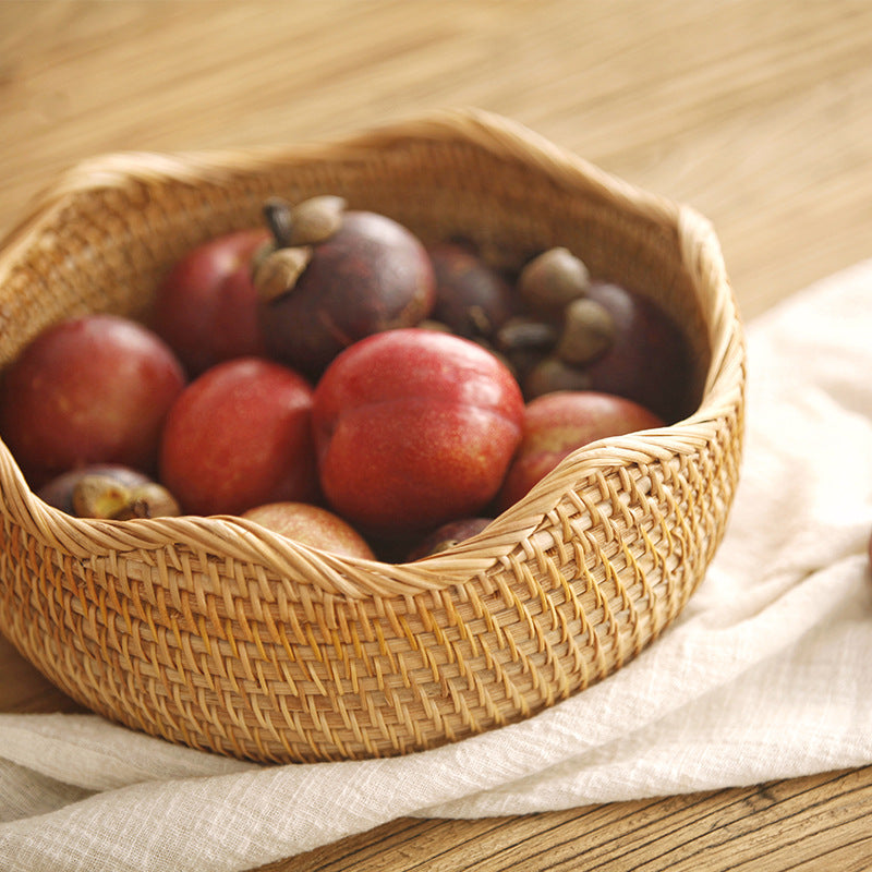 Wavy-rim woven fruit basket filled with mangosteens on a linen cloth and wooden table