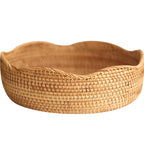 Round woven fruit basket with a wavy scalloped rim on a plain white background
