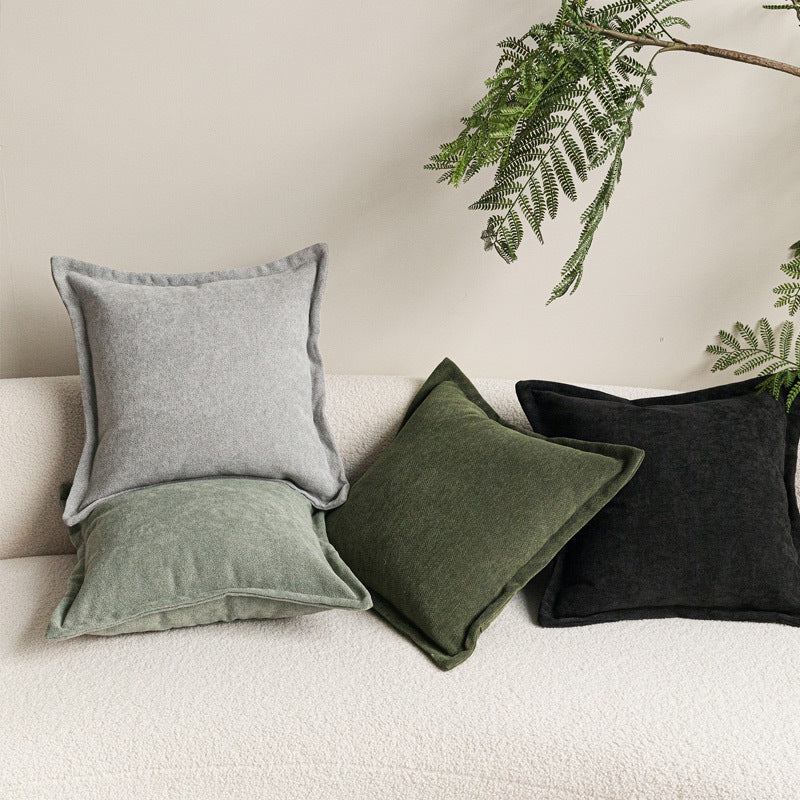 Wide flange-edge chenille pillow covers in grey, moss green, olive and charcoal on a cream bouclé sofa