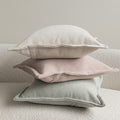 Wide flange-edge chenille pillow covers in oatmeal, dusty rose and sage stacked on a cream sofa