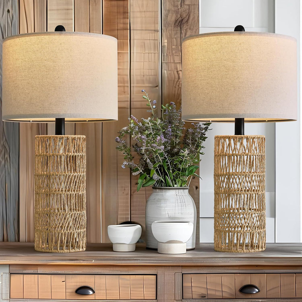 Two woven rattan table lamps lit on a wood console with lavender in a vase (each sold separately)