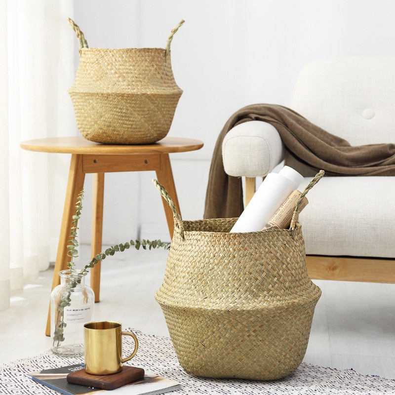 Two seagrass belly baskets, one on a wood stool and one on the floor holding rolled paper