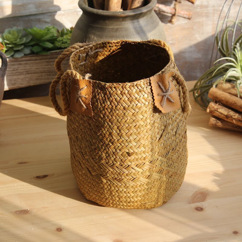 Caramel brown seagrass plant basket with rope handles on a sunlit wooden table