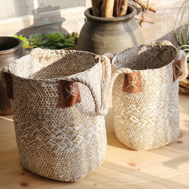 Two whitewashed sand seagrass baskets, large and small, with brown stitched tags at the handles